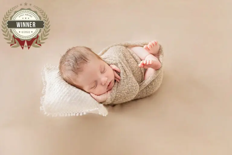 Een baby geposeerd tijdens een geposeerde newbornsessie in de studio/award winning foto