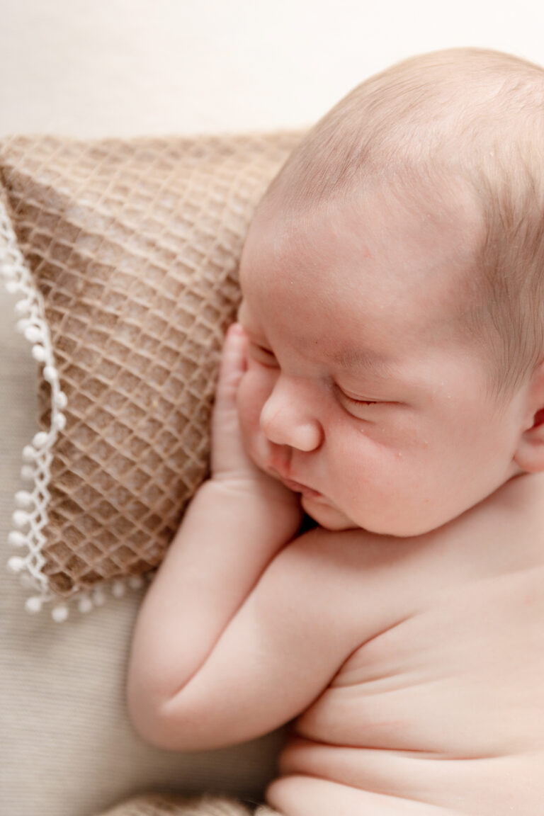 Een baby geposeerd tijdens een geposeerde newbornsessie in de studio