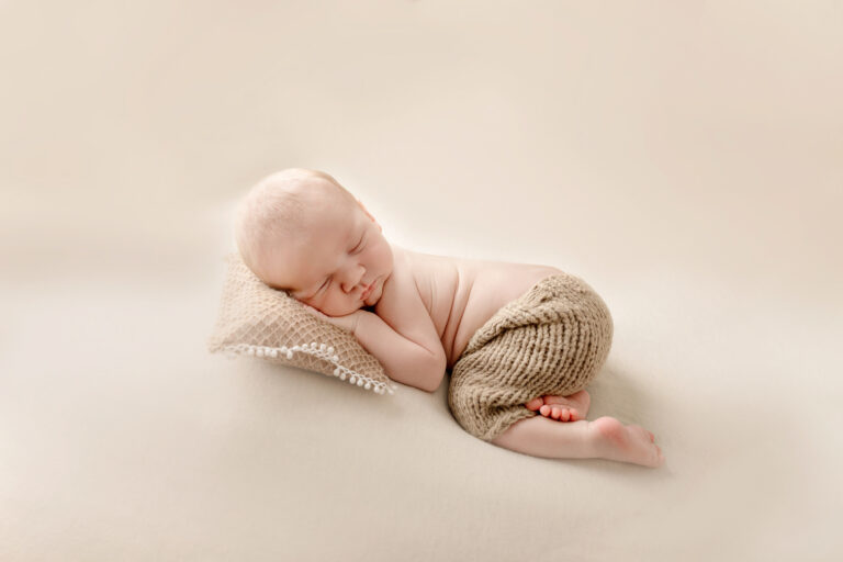 Een baby geposeerd tijdens een geposeerde newbornsessie in de studio