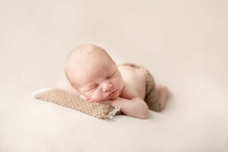 Een baby geposeerd tijdens een geposeerde newbornsessie in de studio