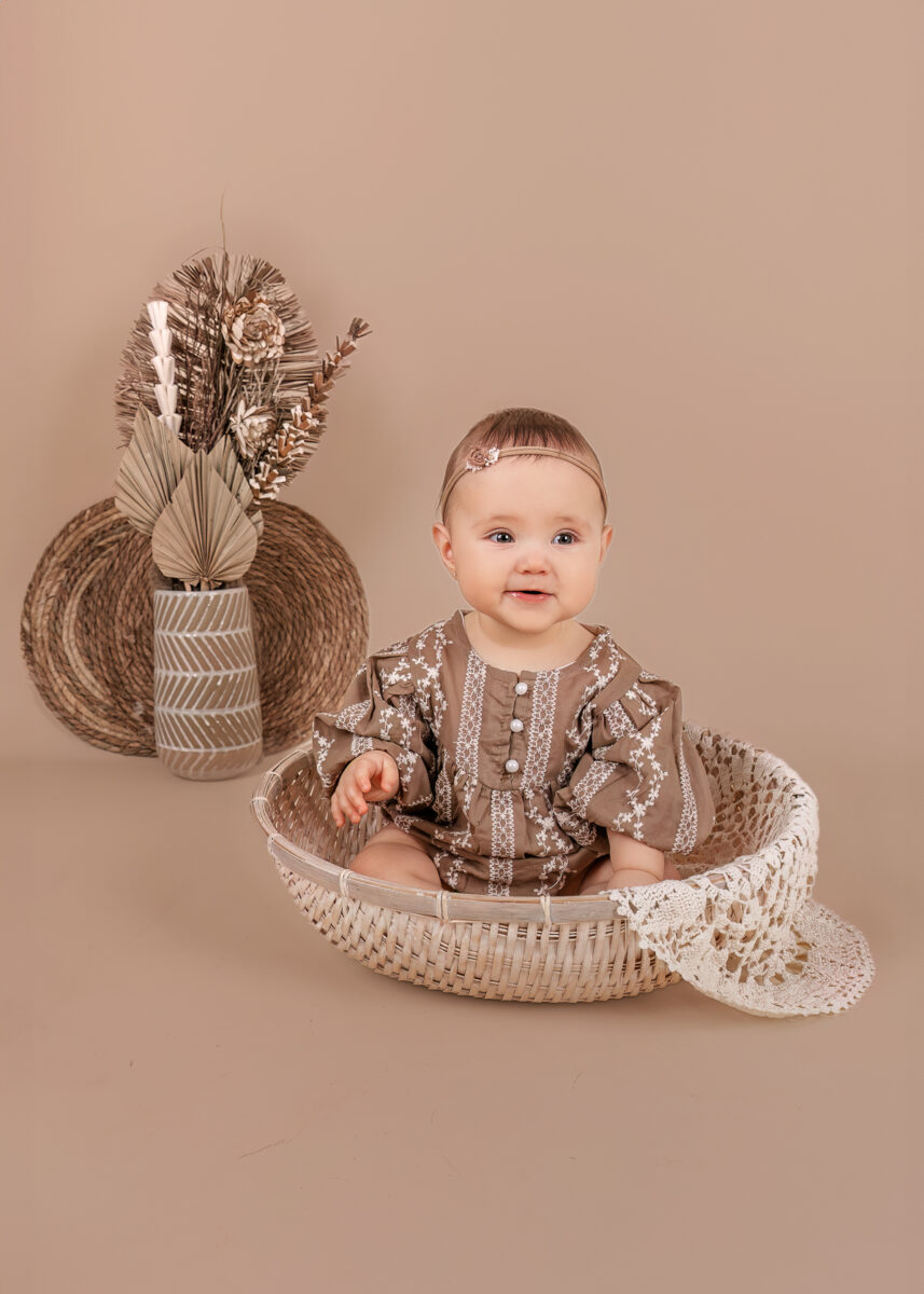 Schattig klein meisje tijd in een witte rieten mand tijdens een sittershoot
