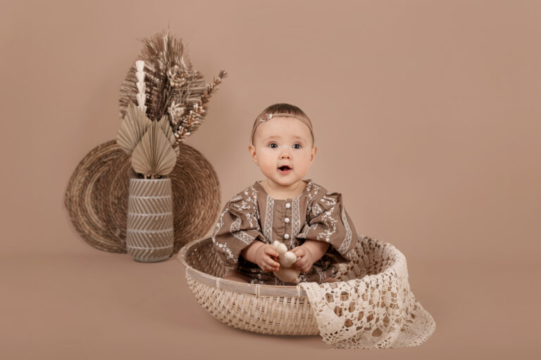 Schattig klein meisje tijd in een witte rieten mand tijdens een sittershoot