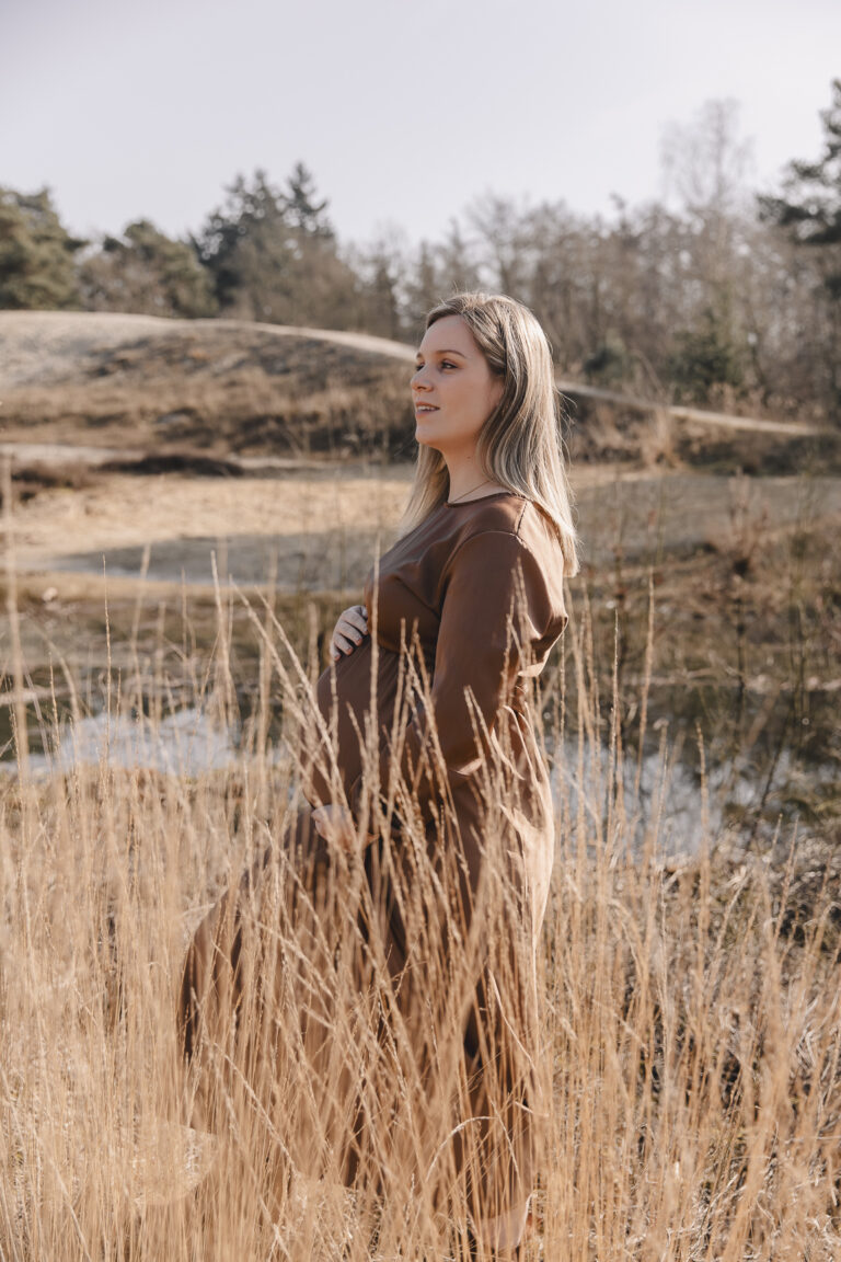 Prachtige vrouw tijdens haar zwangerschapshoot tussen het riet en water