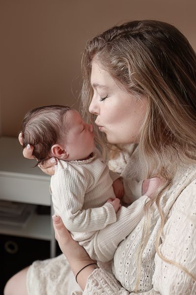 Moeder met pasgeboren baby tijdens newborn lifestyle fotoshoot aan huis